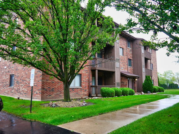 Front view of a multi-story brick apartment building with balconies.