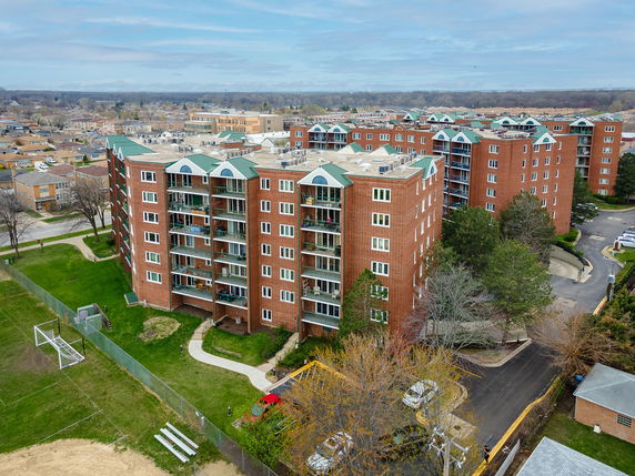 Aerial view of a multi-story brick apartment complex with balconies.