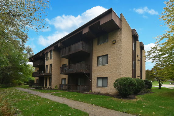 Front view of a three-story apartment building with balconies and a flat roof.