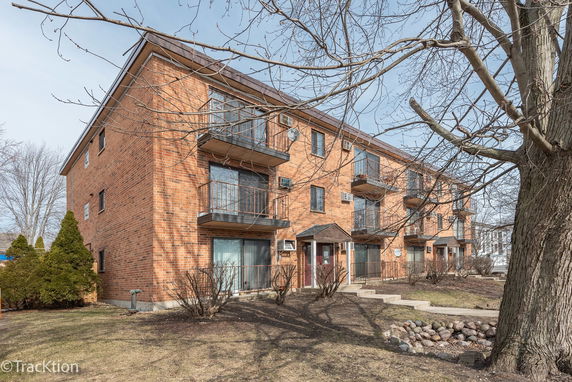 Front view of a multi-story brick apartment building with balconies.