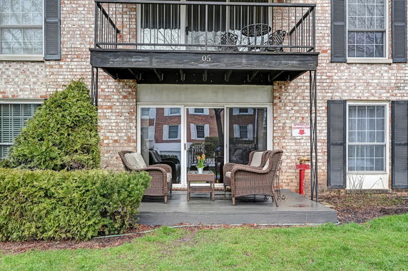 Front view of a brick building with a balcony and patio area.