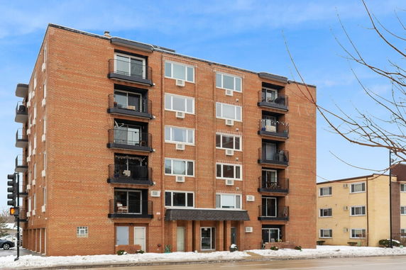 Front view of a multi-story brick apartment building with balconies.