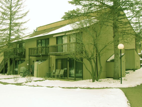 Front view of a multi-story building with balconies and a sloped roof.