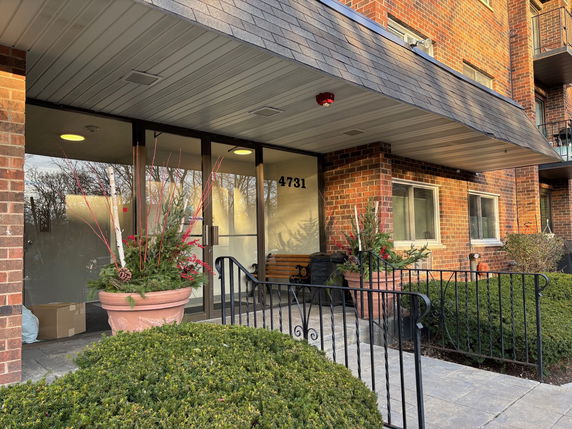 Front view of a building entrance with brick facade and glass doors.