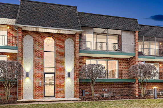 Front view of a two-story brick building with balconies and a central entrance.