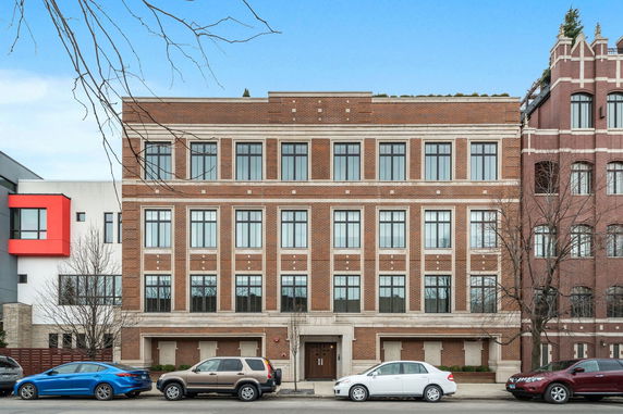 Front view of a multi-story brick building with large windows.