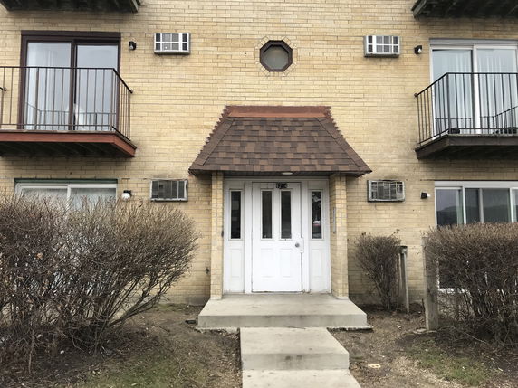 Front view of an apartment building with a central entrance and balconies on either side.