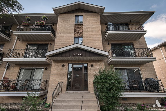 Front view of a three-story brick building with balconies.