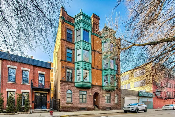 Front view of a multi-story brick building with bay windows.