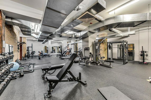 Interior of a gym area with exercise equipment and weights.