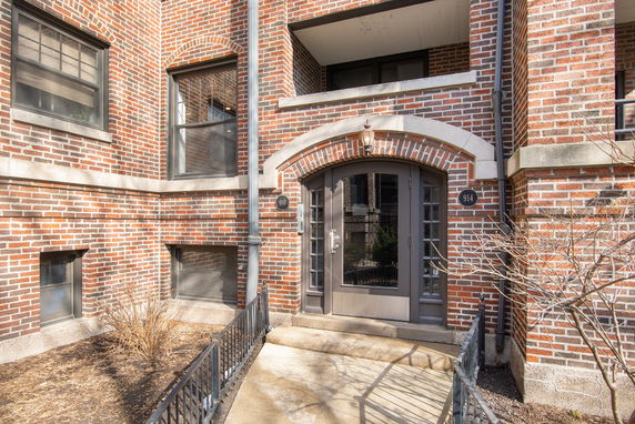 Front view of a brick building entrance with windows and an arched doorway.