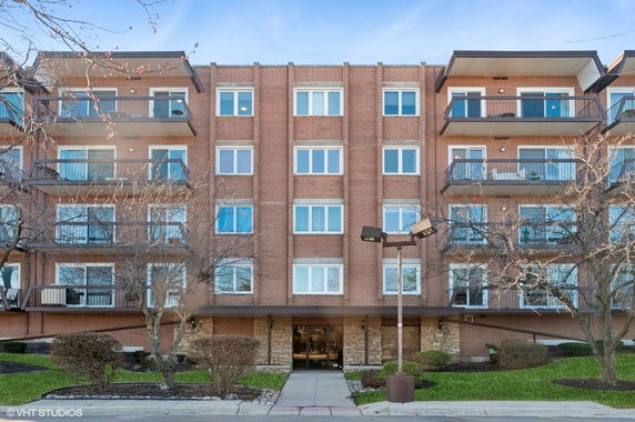 Front view of a multi-story brick apartment building with balconies.