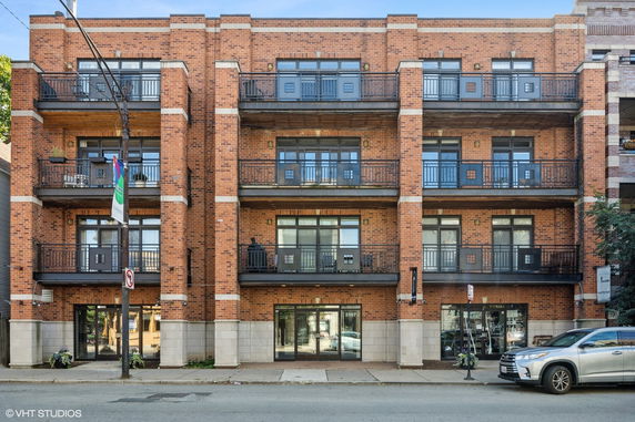Front view of a brick multi-story apartment building with balconies.