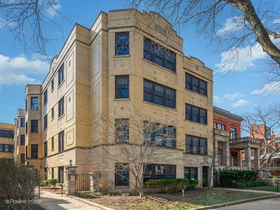 Front view of a multi-story brick building with large windows.