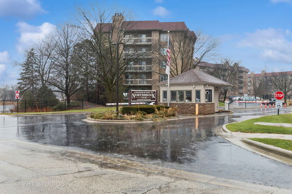 Front view of a condominium complex with multiple buildings and a security guardhouse.