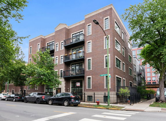 Front view of a brick apartment building with balconies.