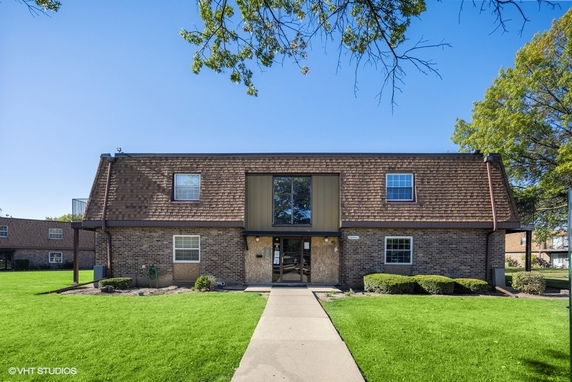 Front view of a two-story brick building with a gabled roof and large central entrance.
