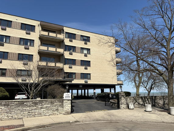Front view of a multi-story apartment building with parking underneath.