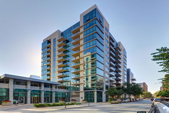 Front view of a modern multi-story building with glass balconies.