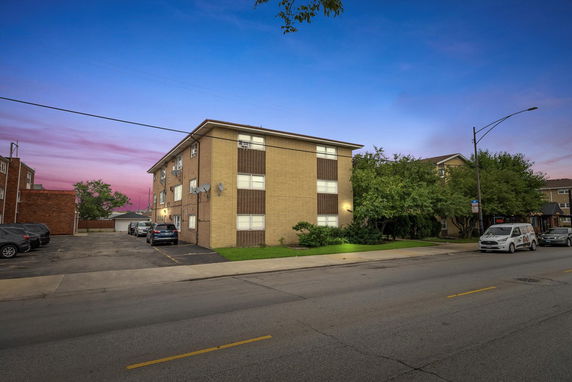 Front view of a three-story residential building with brick exterior and multiple windows.