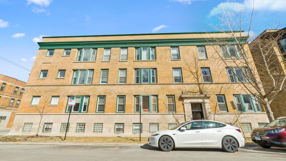 Front view of a multi-story brick building with green window frames.