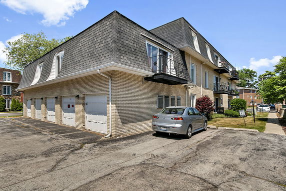 Front view of a multi-story building with garages and balconies.
