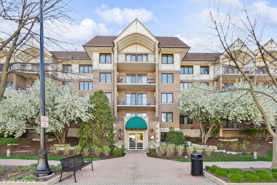 Front view of a multi-story apartment building with a central entrance and balconies.