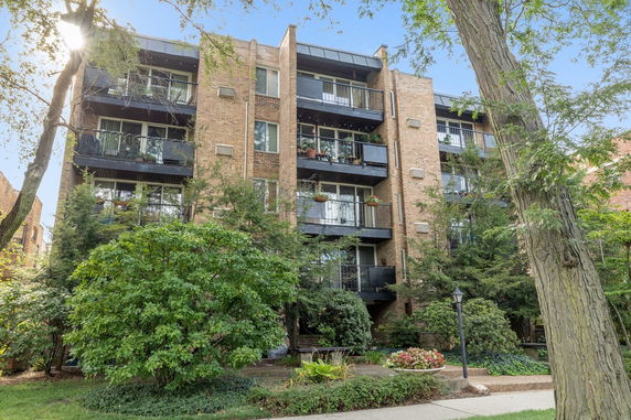 Front view of a multi-story brick apartment building with balconies.
