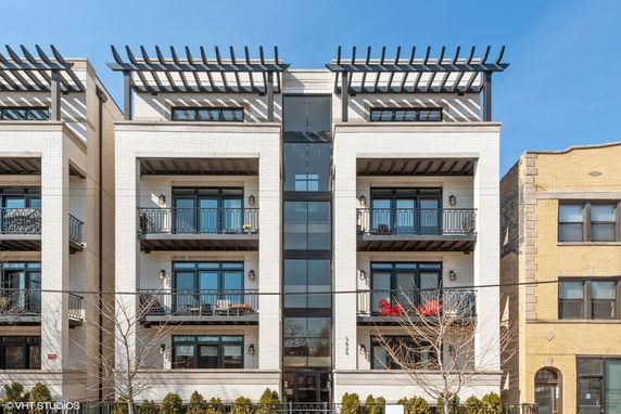 Front view of a multi-story apartment building with balconies and large windows.