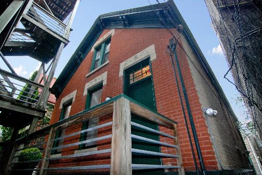 Front view of a brick house with green trim and metal railing.