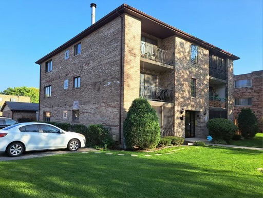 Front view of a three-story brick apartment building with balconies.