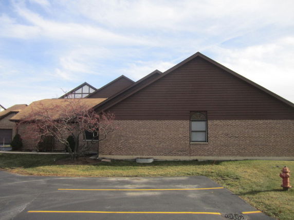 Side view of a brick and wood building with a gable roof.