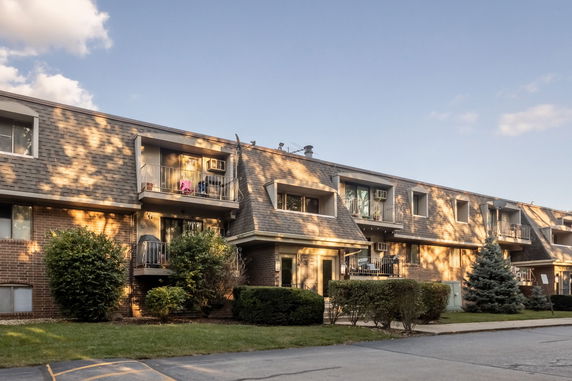 Front view of a multi-story residential building with balconies and a sloped roof.