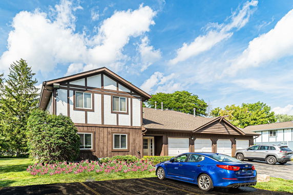 Front view of a two-story house with a garage and parked cars.