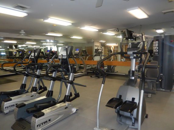 Interior of a gym with exercise equipment including ellipticals and treadmills.
