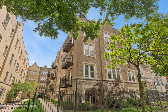 Front view of a multi-story brick apartment building with balconies.