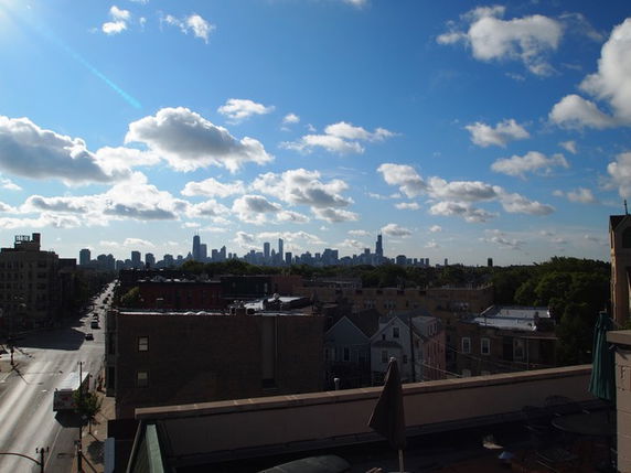 Panoramic view of a city skyline from a rooftop on a sunny day.