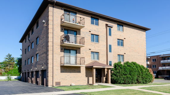 Front view of a four-story brick apartment building with balconies