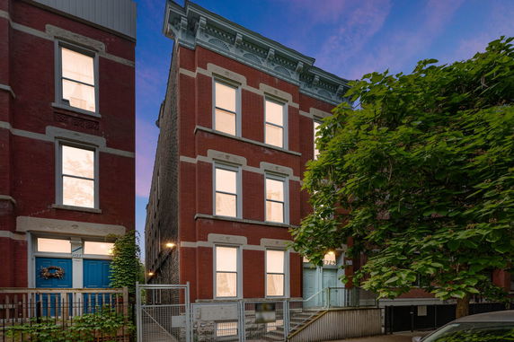 Front view of a brick multi-story residential building with decorative trim and multiple windows.