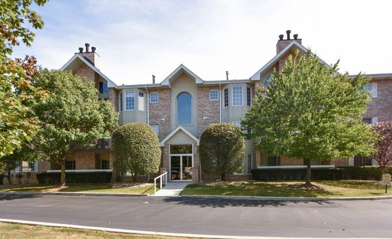 Front view of a three-story residential building with brick and stucco exterior.