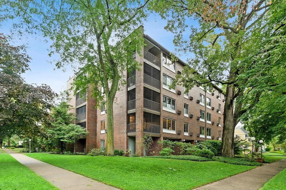 Front view of a multi-story brick apartment building with balconies.