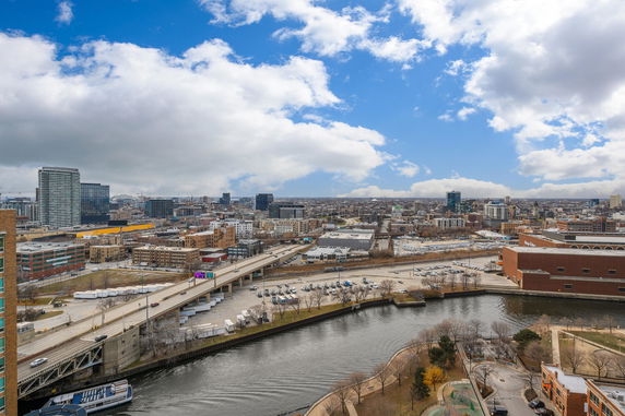 Panoramic view of a cityscape with buildings, a river, and a highway.