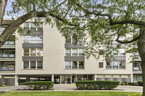 Front view of a multi-story apartment building with large windows and a central entrance.