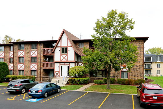 Front view of a multi-story brick building with a gabled roof and balconies.