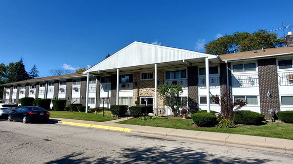 Front view of a two-story apartment building with a porch and vertical columns.