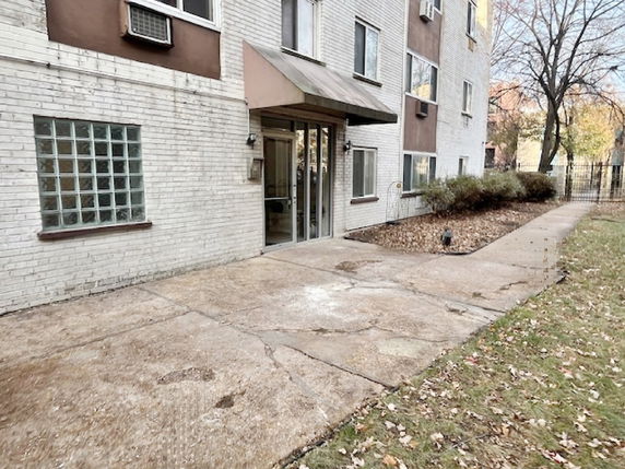 Entrance view of a multi-story brick building with glass block window and air conditioning units.