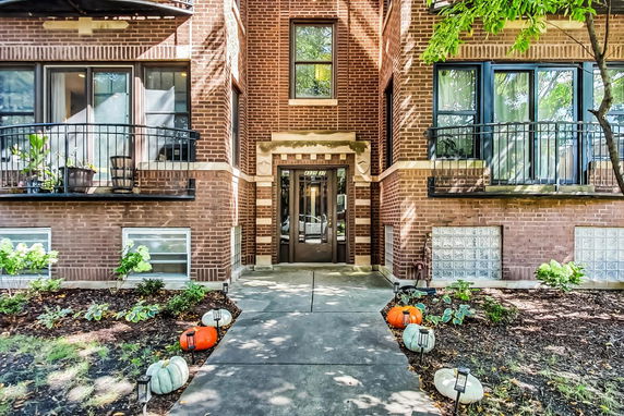 Front view of a brick building with a main entrance and decorative pumpkins.