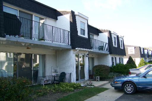 Front view of a two-story residential building with balconies and a driveway.