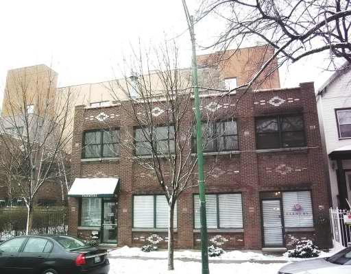 Front view of a two-story brick building with several windows and a small awning above the entrance.
