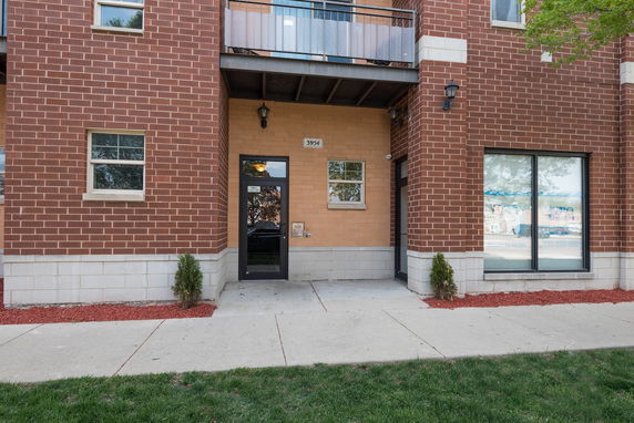 Front view of a multi-story brick building with a glass door entrance and windows.
